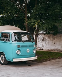 blue and white volkswagen t-2 parked beside white concrete wall during daytime